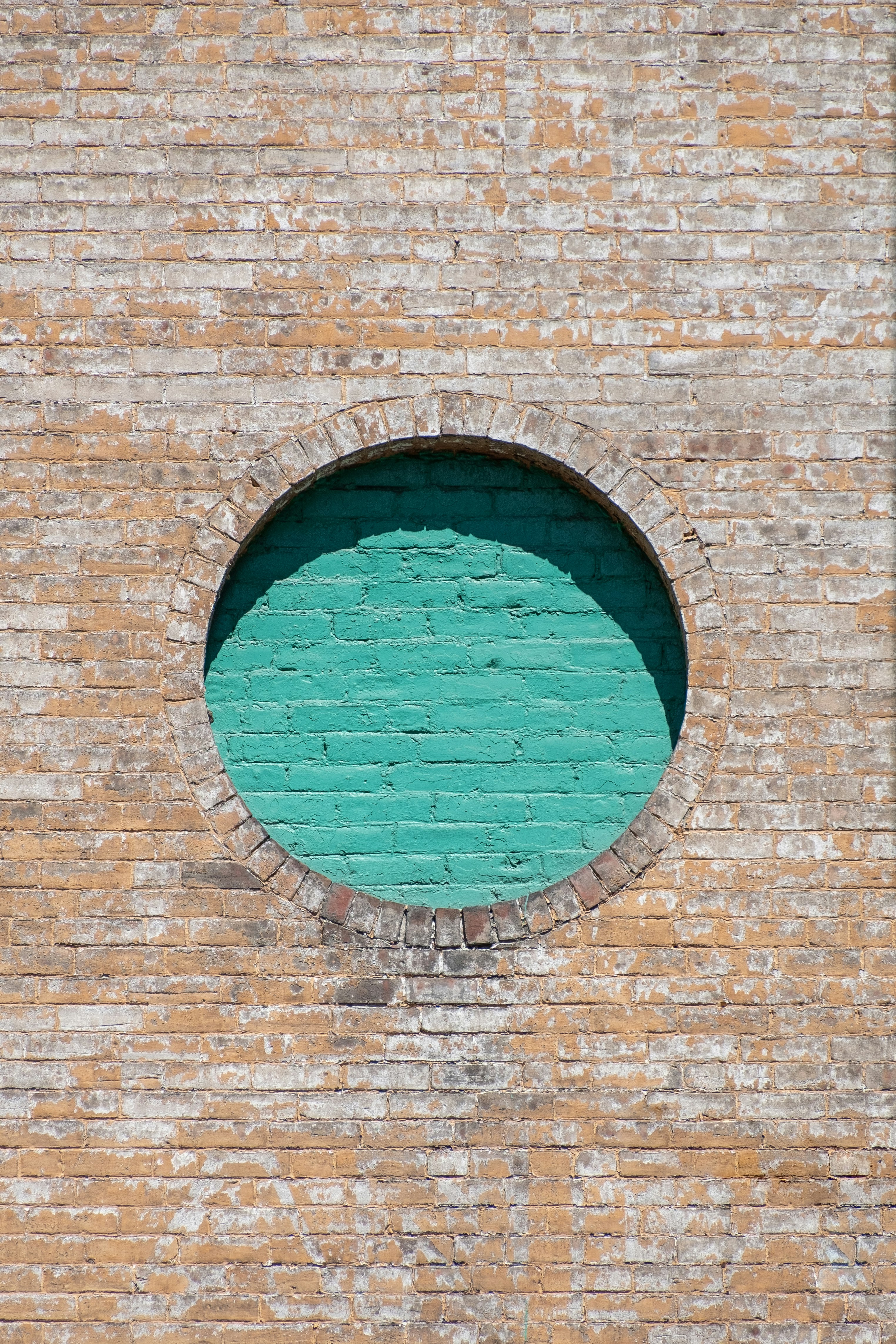 brown brick wall with blue round glass window